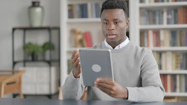 Afričan dělá video hovor na tabletu v knihovně — Stock fotografie
