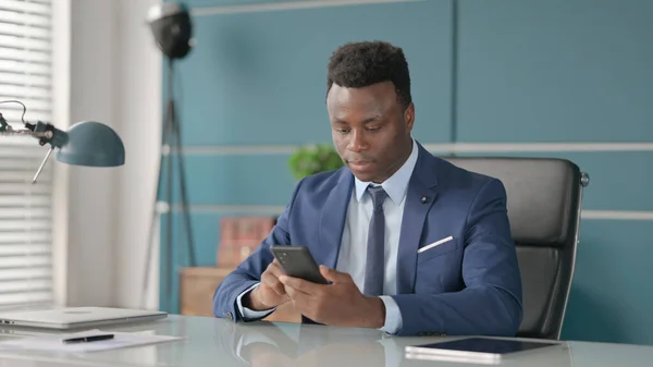 Attrayant homme d'affaires africain en utilisant Smartphone dans le bureau — Photo