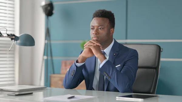 Pensive African Businessman myšlení zatímco sedí v kanceláři — Stock fotografie