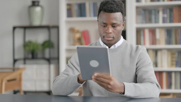 Homem Africano usando Tablet enquanto está sentado na biblioteca — Fotografia de Stock