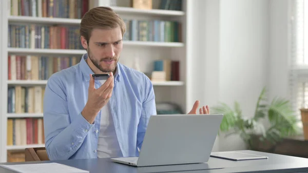 Hombre se siente enojado en el Smartphone mientras usa el ordenador portátil — Foto de Stock
