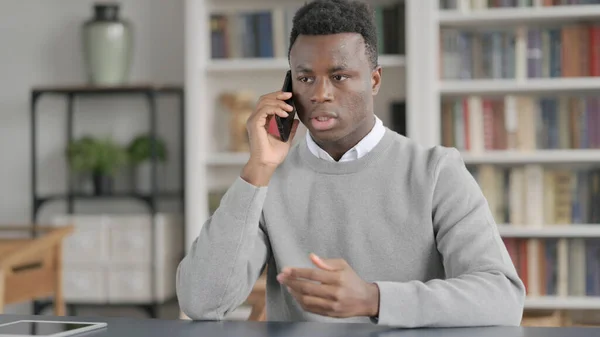 Africano falando ao telefone na biblioteca — Fotografia de Stock