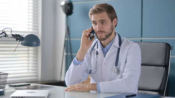 Arts praten over de telefoon tijdens het zitten in de kliniek — Stockfoto