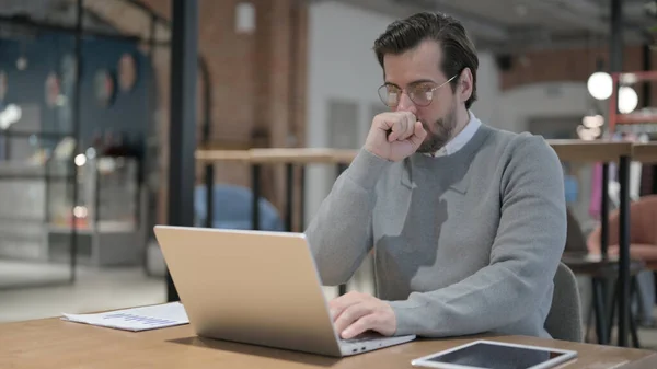Jonge man hoesten tijdens het gebruik van Laptop in Office — Stockfoto