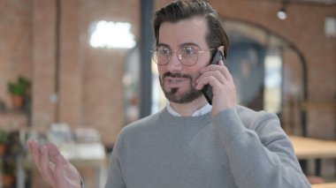 Genç adam telefonda konuşuyor.