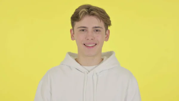 Jovem sorrindo para a câmera em fundo amarelo — Fotografia de Stock