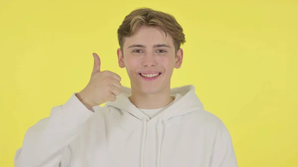 Молодой человек показывает пальцем вверх знак на желтом фоне — стоковое фото