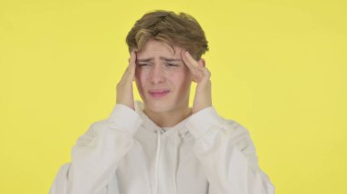 Genç adamın sarı arka planda baş ağrısı var.