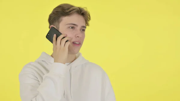 Unge man talar i telefon på gul bakgrund — Stockfoto