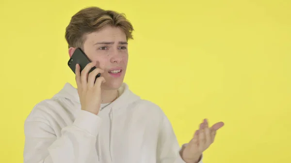 Joven hablando enojado en el teléfono sobre fondo amarillo —  Fotos de Stock