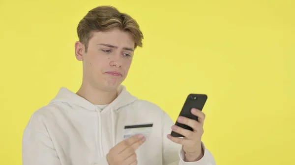 黄色の背景に男によるスマートフォンでオンラインショッピングの失敗 — ストック写真