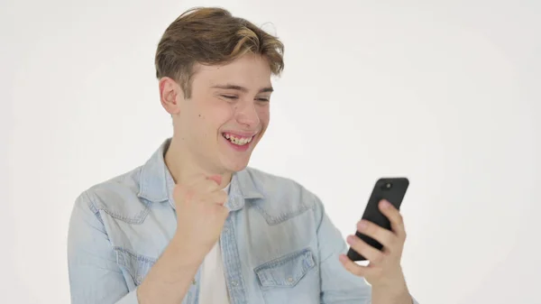 Молодой человек празднует на смартфоне на белом фоне — стоковое фото