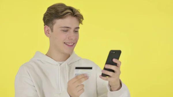 Молодий чоловік онлайн покупки на смартфоні на жовтому тлі — стокове фото