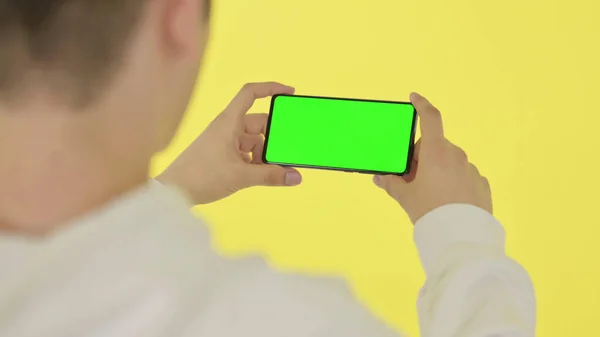 Watching Horizontal Smartphone with Green Screen, Yellow Background — Stock Photo, Image