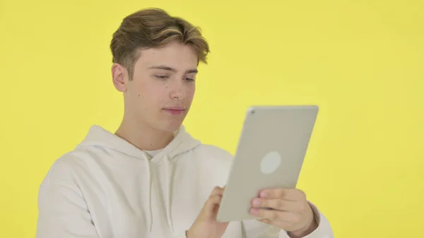 Hombre joven usando tableta digital sobre fondo amarillo —  Fotos de Stock