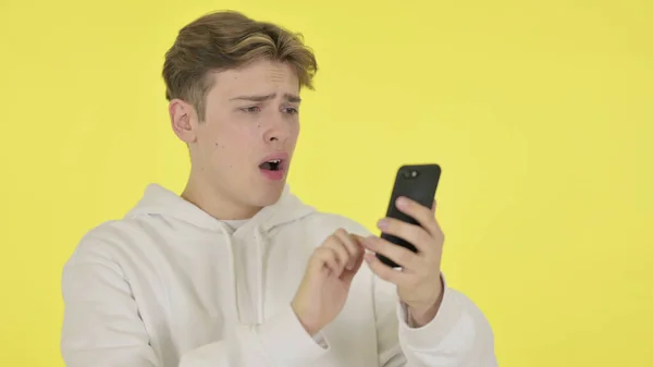 若い男損失上のスマートフォン黄色の背景 — ストック写真