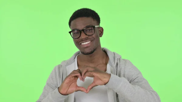 Африканський чоловік показує форму серця руками на зеленому тлі — стокове фото