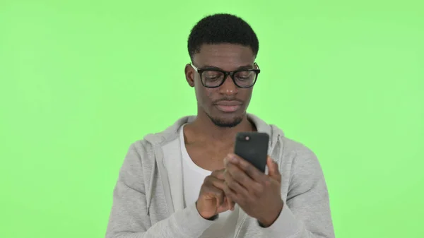 Yeşil Arkaplanda Afrikalı Adam Akıllı Telefona Bakıyor — Stok fotoğraf