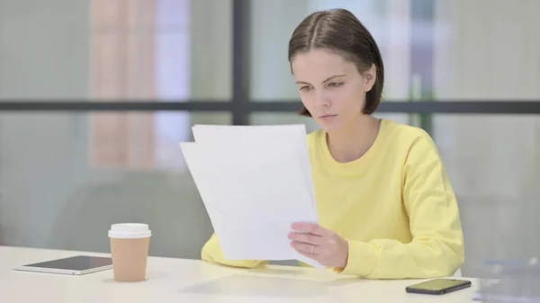 Mladá žena čte zprávy, zatímco sedí v kanceláři — Stock fotografie