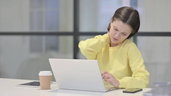 Mujer joven que tiene dolor de cuello mientras usa el ordenador portátil en la oficina — Foto de Stock