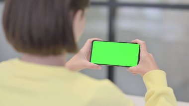 Woman Looking at Smartphone with Green Screen, Rear View