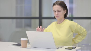 Ofiste dizüstü bilgisayar kullanırken Sırt Ağrısı Olan Genç Kadın