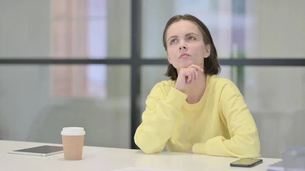 Pensive jeune femme pensant tout en étant assis au bureau — Photo
