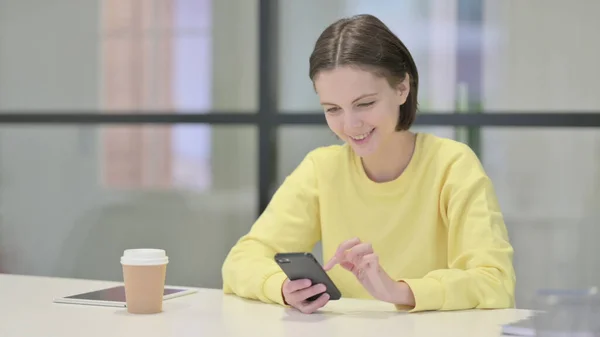 Молодая женщина с помощью смартфона в офисе — стоковое фото
