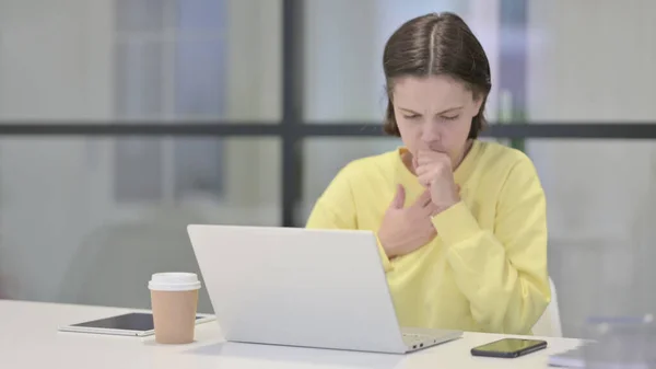 Mujer joven tosiendo mientras usa el ordenador portátil en la oficina — Foto de Stock