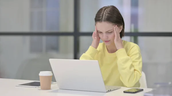 Ung kvinna med huvudvärk medan du arbetar på laptop — Stockfoto