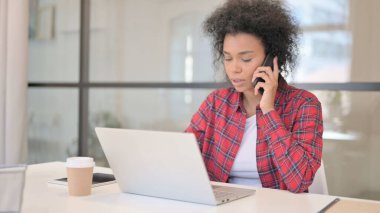 Laptop kullanırken telefonda konuşan Afrikalı Kadın