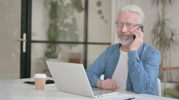 Senior Old Man Talking on Phone while using Laptop — Photo