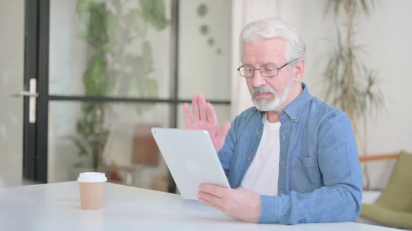 Starší stařec dělá video hovor na tabletu v kanceláři — Stock fotografie