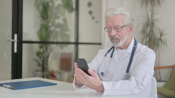 Senior Old Doctor using Smartphone in Clinic — стоковое фото