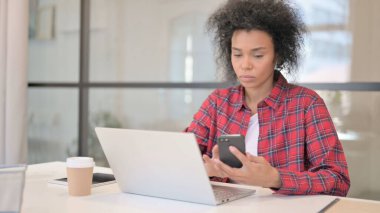 Laptop kullanırken Akıllı Telefon kullanan Afrikalı Kadın