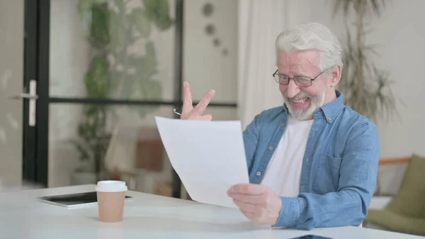 Vieil homme âgé célébrant le succès tout en lisant des documents au bureau — Photo
