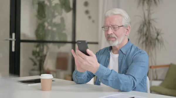 Älterer Mann nutzt Smartphone im Büro — Stockfoto