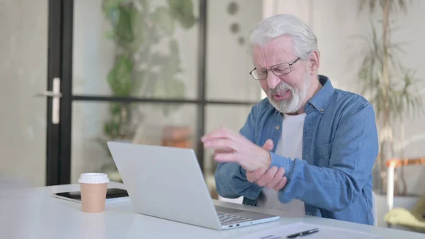 Älterer Mann hat Handgelenkschmerzen, während er Laptop im Büro benutzt — Stockfoto