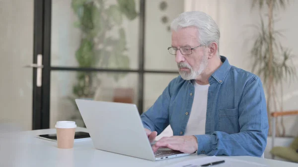 Vieil homme âgé travaillant sur ordinateur portable au bureau — Photo