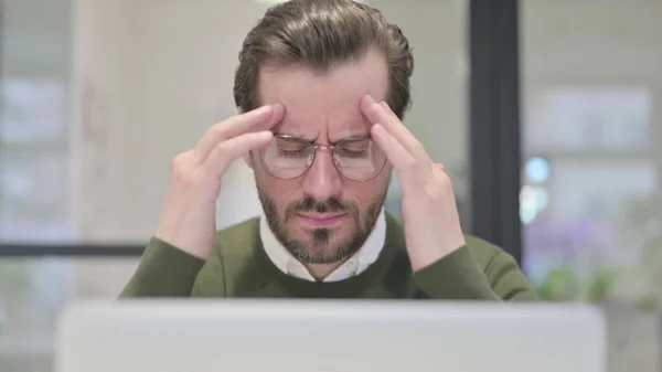 Nahaufnahme eines jungen Geschäftsmannes, der Kopfschmerzen hat, während er Laptop benutzt — Stockfoto