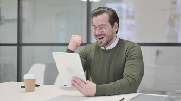 Giovane uomo d'affari che celebra il successo sul tablet in ufficio — Foto Stock