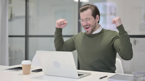 Giovane uomo d'affari che celebra il successo durante l'utilizzo del computer portatile in ufficio — Foto Stock