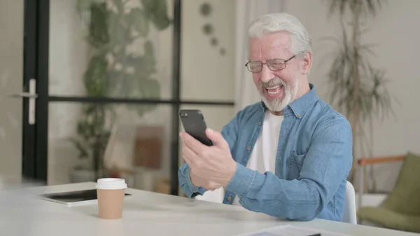 Vieil homme âgé couronné de succès Célébrant le succès sur Smartphone au bureau — Photo