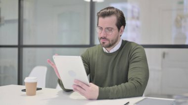 Ofiste otururken Tablet kullanan Genç İşadamı