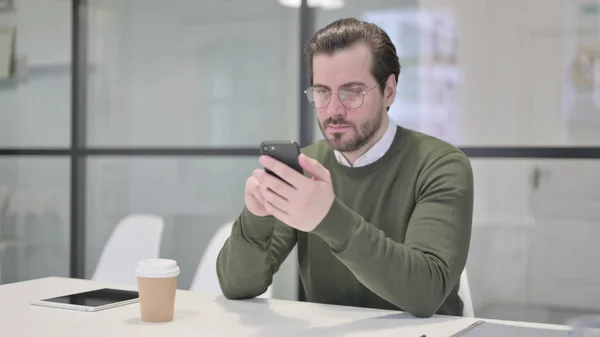 Молодой бизнесмен с помощью смартфона в офисе — стоковое фото