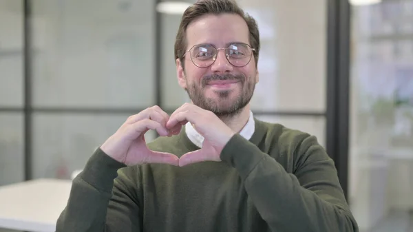 Portrait de jeune homme d'affaires montrant la forme du cœur par les mains — Photo