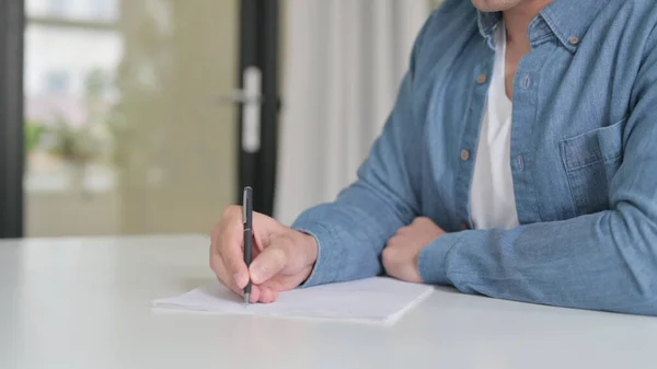 Man Writing on Paper with Pen Stock Photo