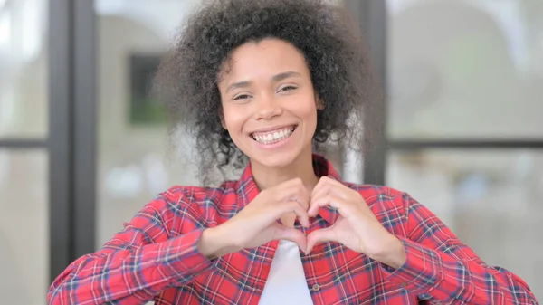 Retrato de una mujer africana mostrando la forma del corazón con las manos — Foto de Stock