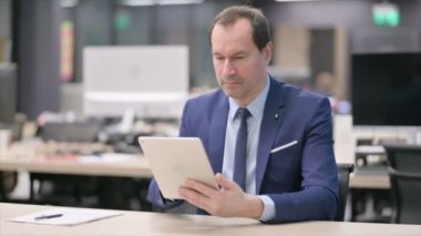 Ofiste otururken Tablet kullanan İşadamı