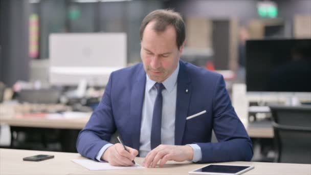 Бизнесмен пишет на бумаге в офисе — стоковое видео